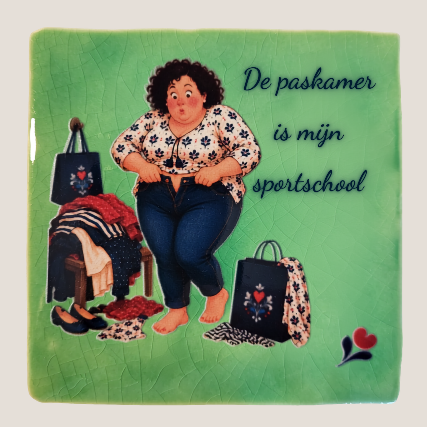 Keramisch tegeltje van De Dametjes van Fryslân met Tryntsje die een spijkerbroek probeert dicht te krijgen en de quote 'De paskamer is mijn sportschool'.