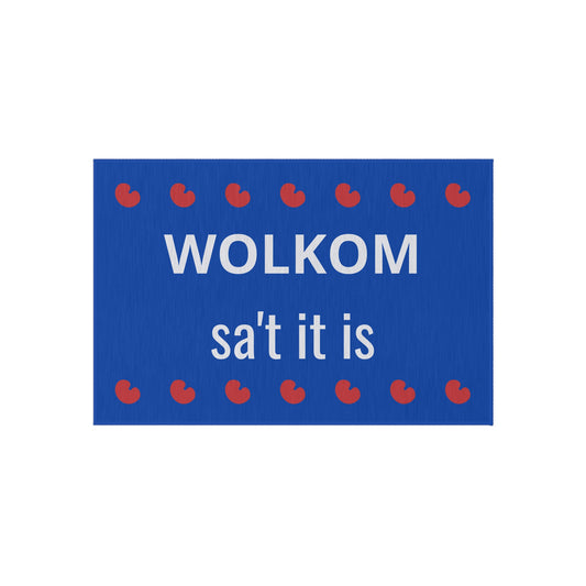 Friese deurmat met blauwe achtergrond, witte tekst “Wolkom, sa’t it is” en rode pompeblêdjes