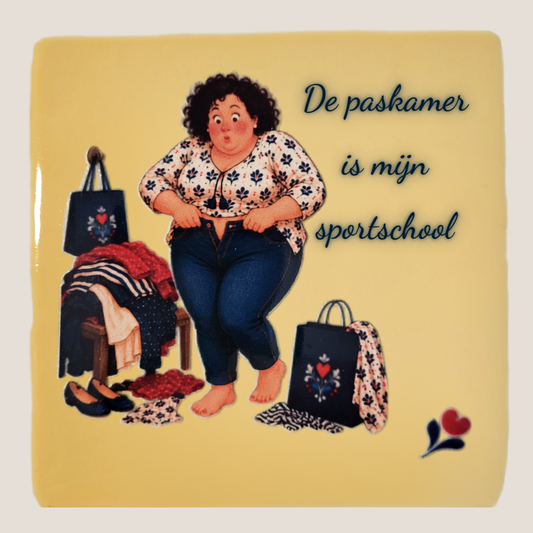 Keramisch tegeltje van De Dametjes van Fryslân met Tryntsje die een spijkerbroek probeert dicht te krijgen en de quote 'De paskamer is mijn sportschool'.