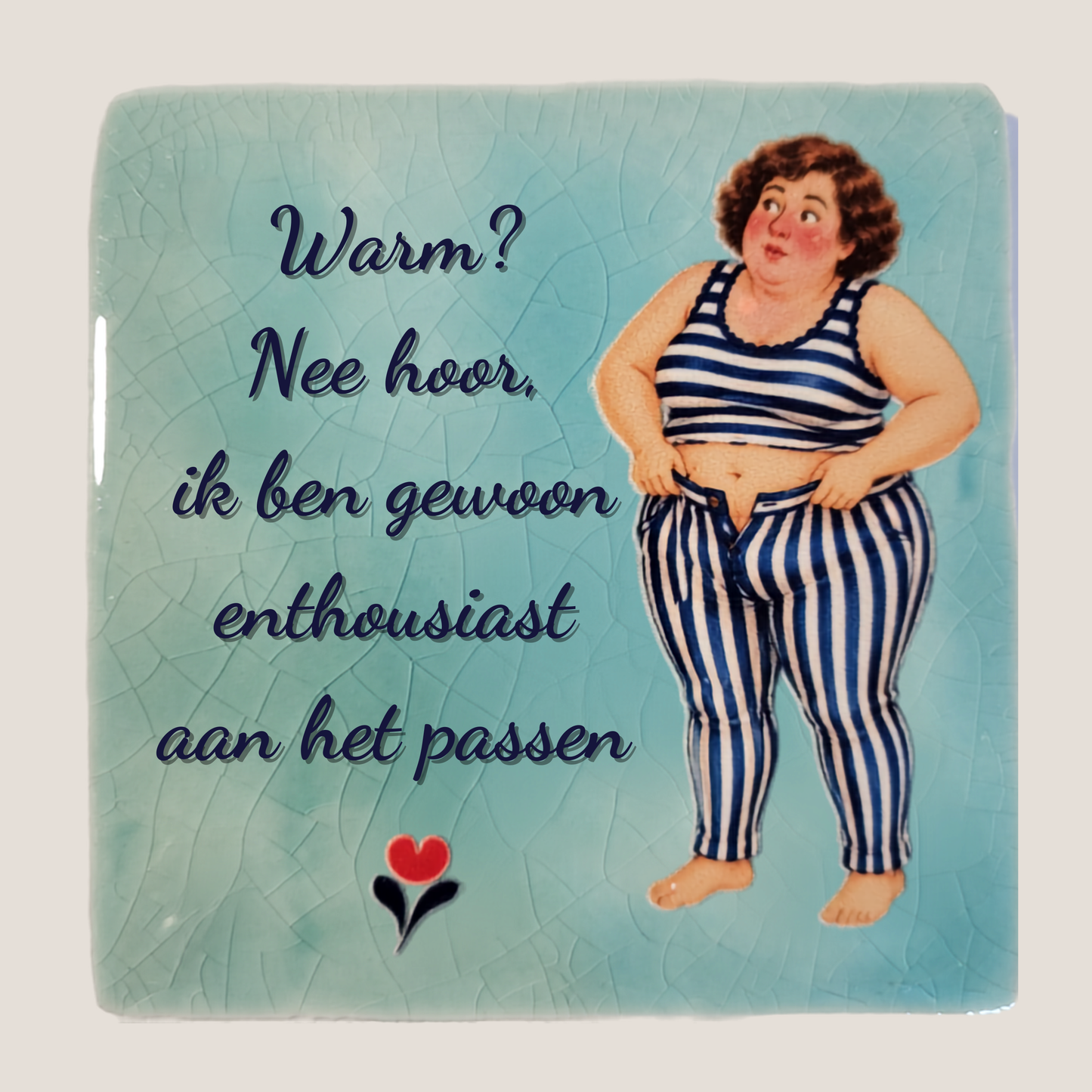 Keramisch tegeltje van De Dametjes van Fryslân met een dametje dat een gestreepte broek probeert aan te trekken en de quote 'Warm? Nee hoor, ik ben gewoon enthousiast aan het passen'.